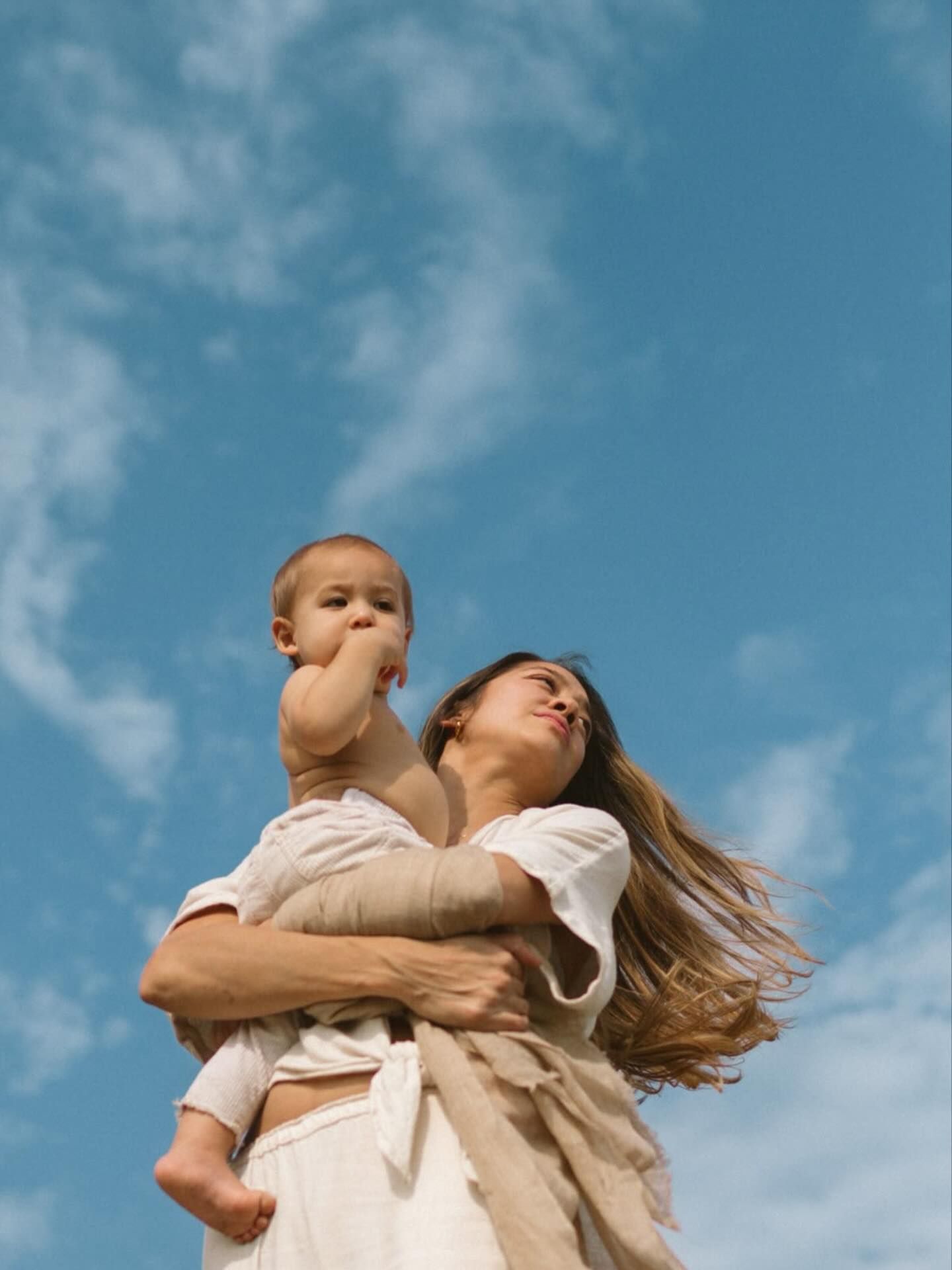 Femme tenant son bébé dans les bras sous un ciel bleu